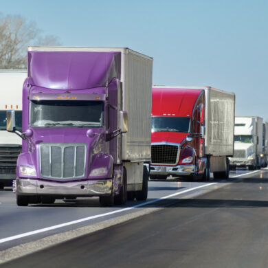 Multi-colored Convoy of Big Trucks Rolls Down The Interstate