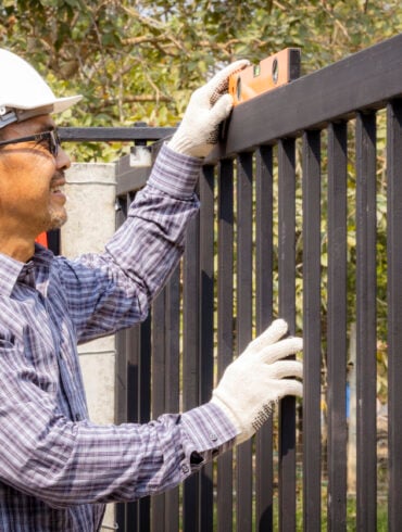 Close-up of half a technician installing a metal door on a very sunny day.