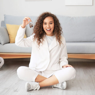 Happy young woman with key in her new flat